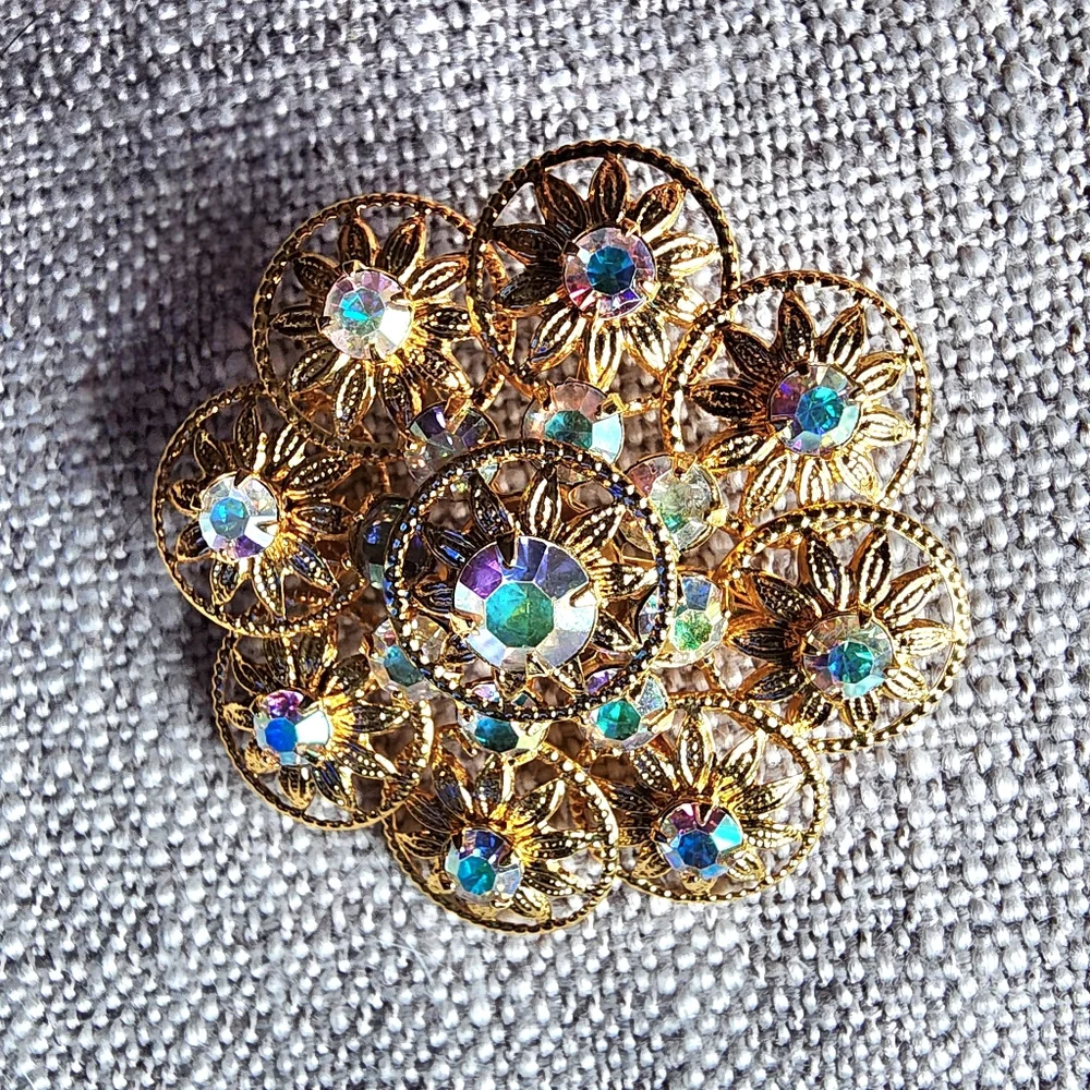 Vintage aurora borealis rhinestone gold-tone filigree floral brooch. 1960's